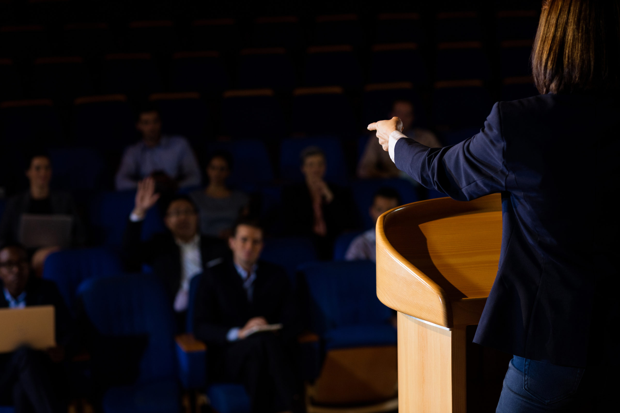 Rear view of female business executive giving a speech at conference center